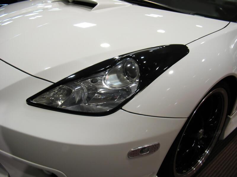 Picture of a white car with tinted windows and a zoomed in look of the headlight